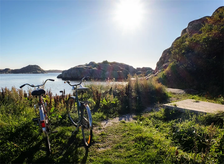 Somrig bild på två cyklar i skärgårdsmiljö.
