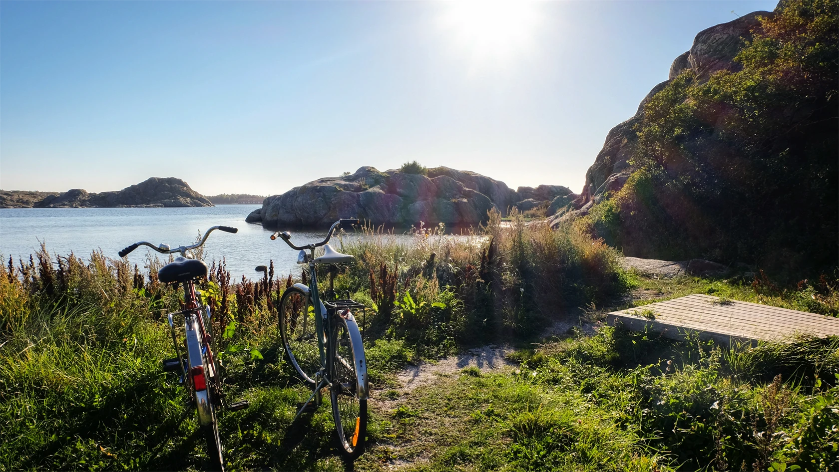 Somrig bild på två cyklar i skärgårdsmiljö.