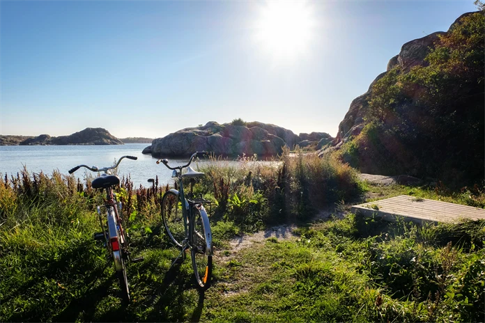 Somrig bild på två cyklar i skärgårdsmiljö.